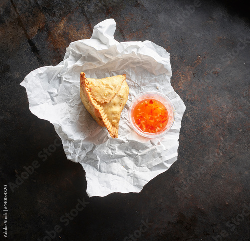 Studio shot of samosa dumpling and bowl of chili sauce on paper napkin photo