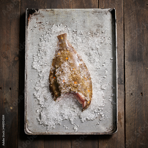 Studio shot of raw half eaten plaice lying on tray with crushed ice