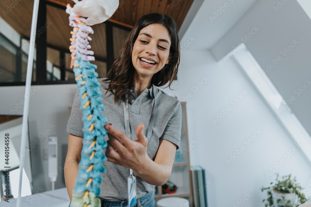 Smiling female trainer explaining spine model in classroom Smiling female trainer explaining spine model in classroom