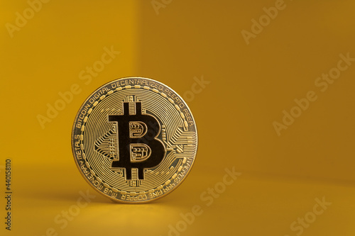 Gold colored bitcoin against yellow background photo
