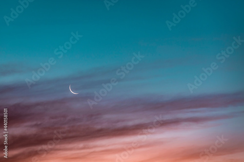 Crescent moon glowing against sky at dusk photo