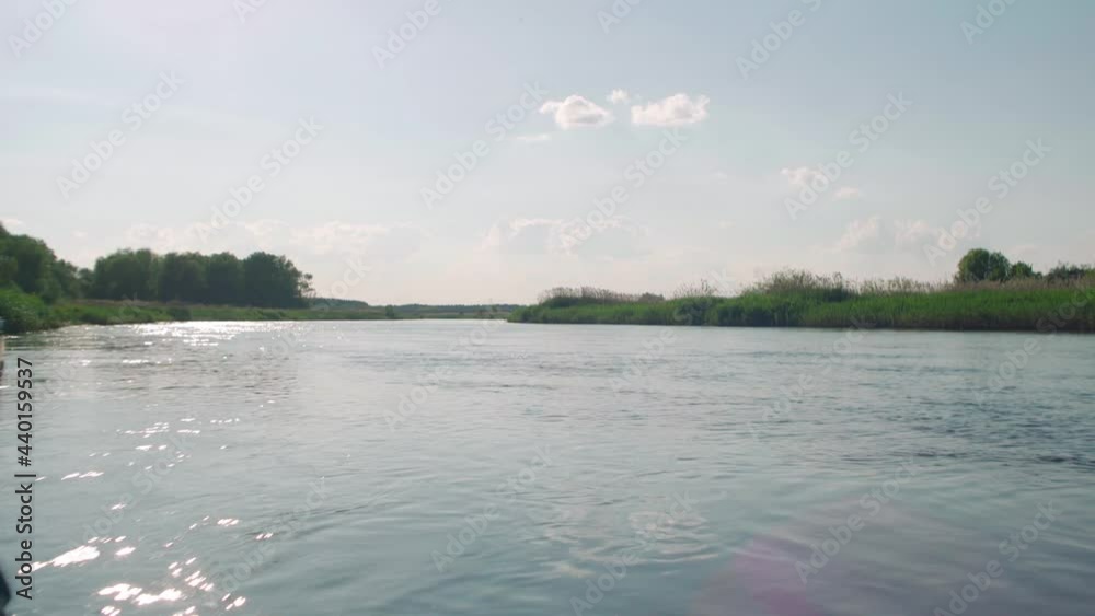 View of tranquility water waves creating glints, and glare on the water surface. View of the forest in the background.