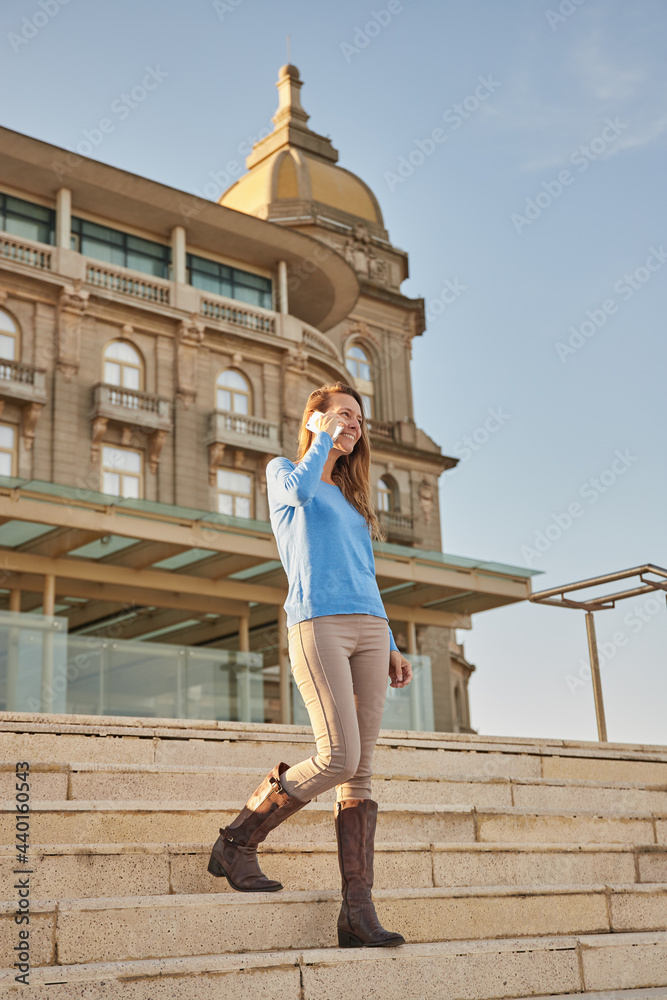Female talking on cellphone while walking in city near building Female talking on cellphone while walking in city near building