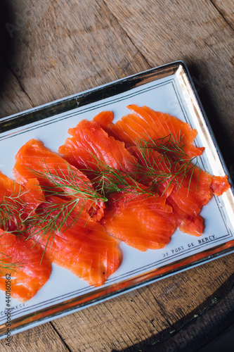 cured salmon lox on plate with dill fennel atop wooden barrel photo