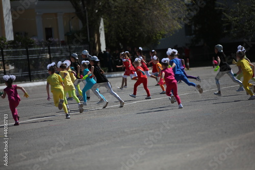 A group of children little girls and boys running in bright tracksuits are doing outdoor sports on the street.The concept of school physical development and child health. Background