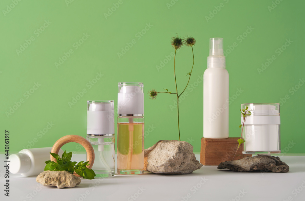 A set of cosmetics products with natural materials on a green background. Stones, plant and wooden decorative figures. Natural organic cosmetic. Beauty concept. Wabi sabi trend