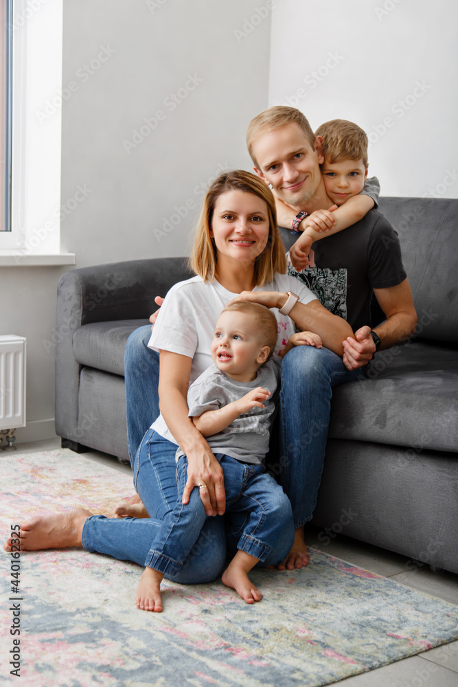 Happy family in casual denim in a living room. Little boys with their mother and father at home. Good morning parent and infant sons in jeans wear. Family weekdays traditions. Relationship with love Happy family in casual denim in a living room. Little boys with their mother and father at home. Good morning parent and infant sons in jeans wear. Family weekdays traditions. Relationship with love