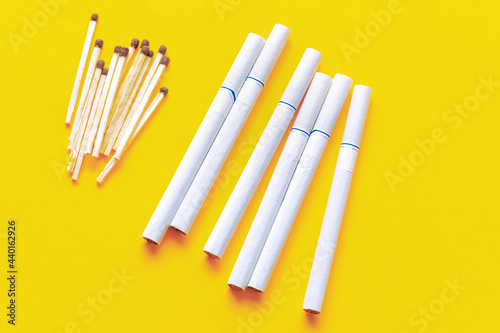 Unhealthy lifestyle concept . Cigarettes and matches at yellow background