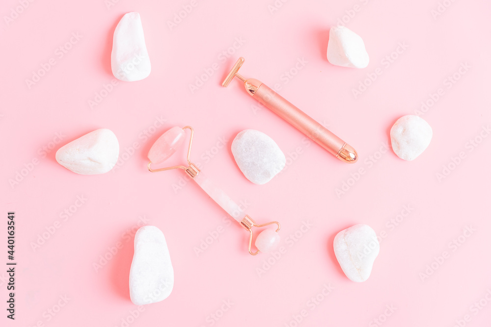 top view of quartz and metal face massagers with white stones copper pink background. skin care concept. personal care. flat lay top view of quartz and metal face massagers with white stones copper pink background. skin care concept. personal care. flat lay