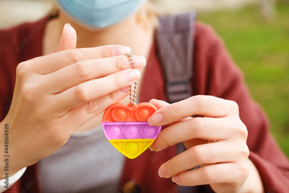 Girl in mask holding rainbow bubble pop it fidget toy. For autistic patients to relieve stress, help restore mood. Squeeze sensory game. Simple dimple. Push pop for homeschool, office, stress reliever Girl in mask holding rainbow bubble pop it fidget toy. For autistic patients to relieve stress, help restore mood. Squeeze sensory game. Simple dimple. Push pop for homeschool, office, stress reliever