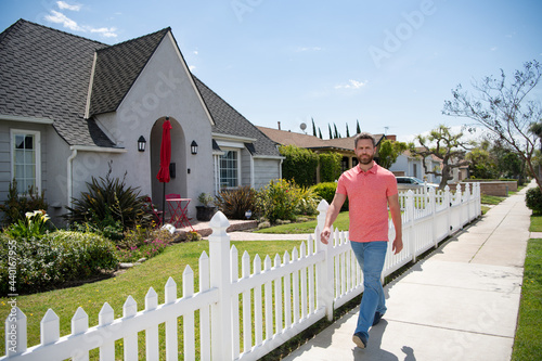 Businessman walkind outside near house, rent new home. photo