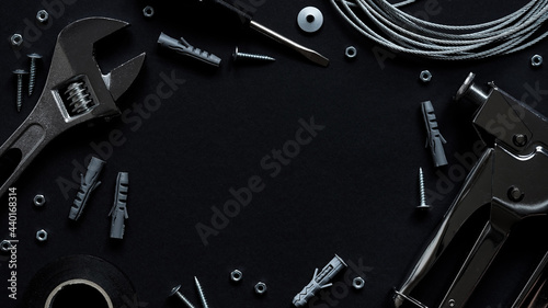 Happy fathers day banner concept. Upholstery repair working tool stapler, screwdriver, screws, adjustable wrench, electrical tape and wire on black background, top view, flat lay, copy space.