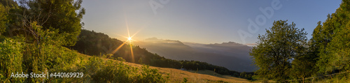 panorama of peaceful morning with sunrise over french alps with meadow in foreground