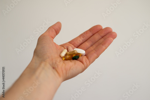 Hand holding a variety of different coloured health supplements