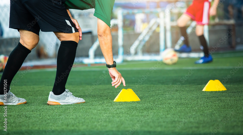 Obraz premium Coach or soccer player is putting the marker cones for soccer training to run and jump. Soccer or football academy.