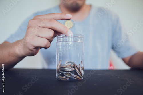 Man holding coins putting in glass, saving money for finance accounting concept.