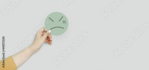 Fototapeta Naklejka Na Ścianę i Meble -  Hand holding green paper cut angry face, positive thinking, mental health assessment , world mental health day concept	