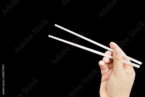  hand holding chopsticks isolated on black background