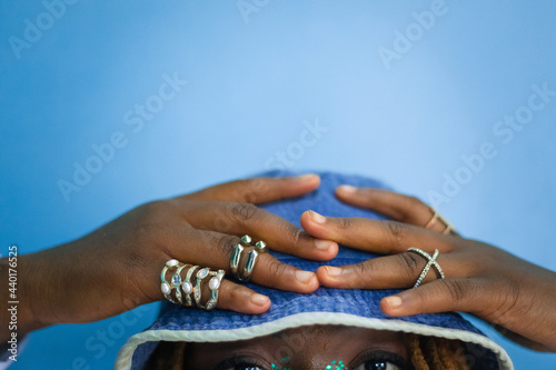 Woman with rings with her hand on denim bucket hat