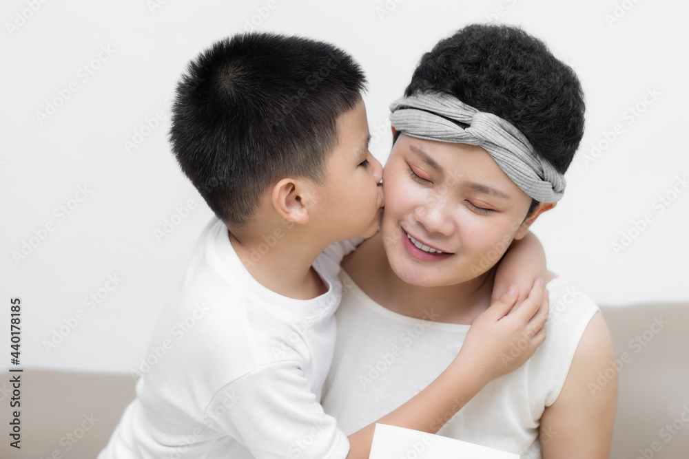 Young adult female cancer patient spending time with little son on gray background. Cancer and family support concept. Young adult female cancer patient spending time with little son on gray background. Cancer and family support concept.
