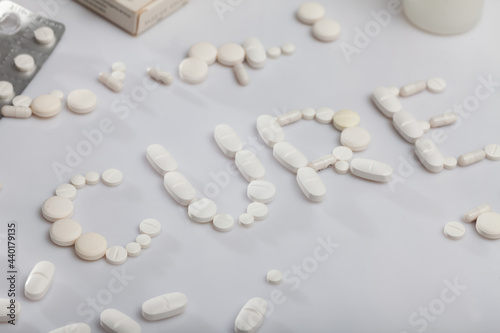 Word CURE from pills and capsules on white background, pharmaceutical industry concept
