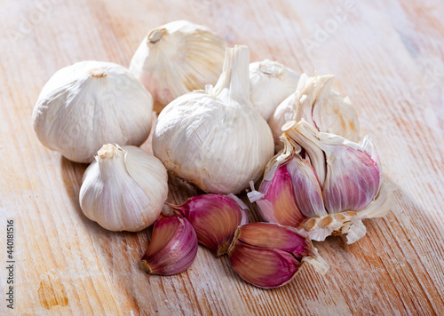 Whole raw garlic with separated cloves on wooden surface..