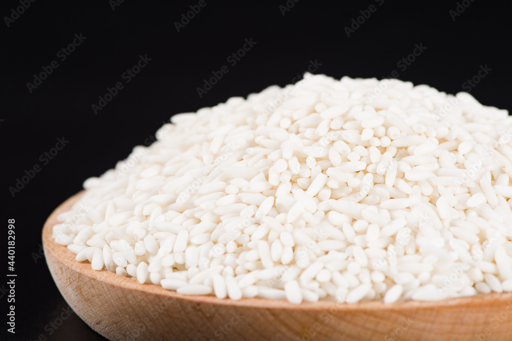 Raw organic white rice on black background, glutinous rice or sticky rice close up Raw organic white rice on black background, glutinous rice or sticky rice close up