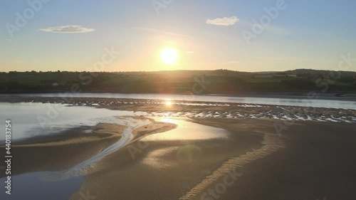 Sun Flare And Reflection On Mudflat With Train Moving On Railway Lydney, Gloucestershire, England. wide shot photo