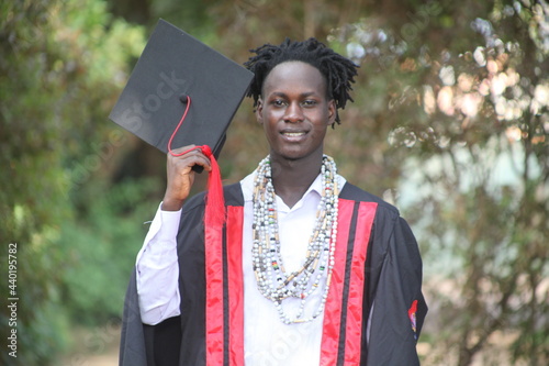 The African traditional man graduates on his graduation day and is looking straight into the camera with a wonderful smile with the African beads in his neck