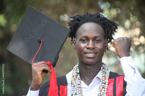 The African traditional man graduates on his graduation day and is looking straight into the camera with a wonderful smile with the African beads in his neck