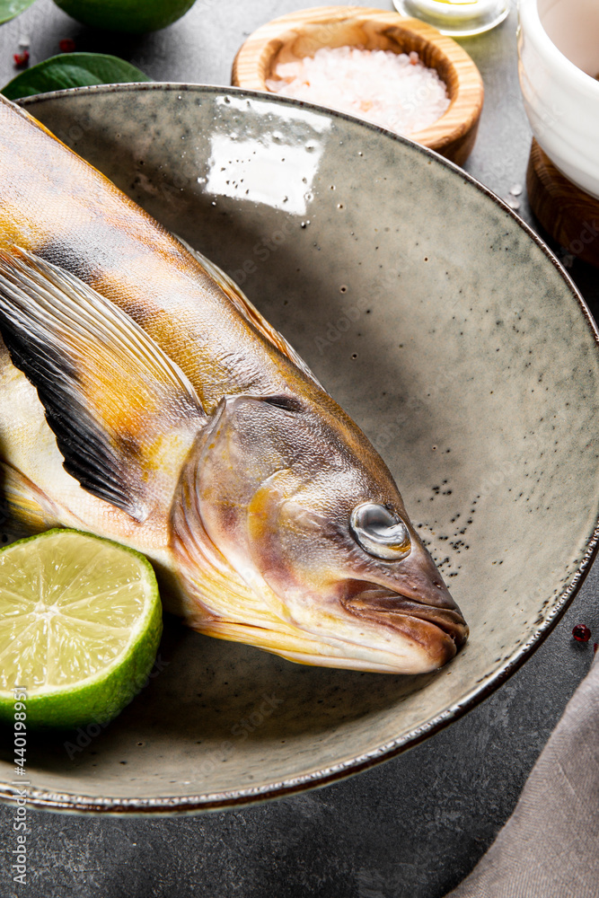  Raw fish sea bass or lingcod and seasonings for cooking it on a table close up vertical photo
