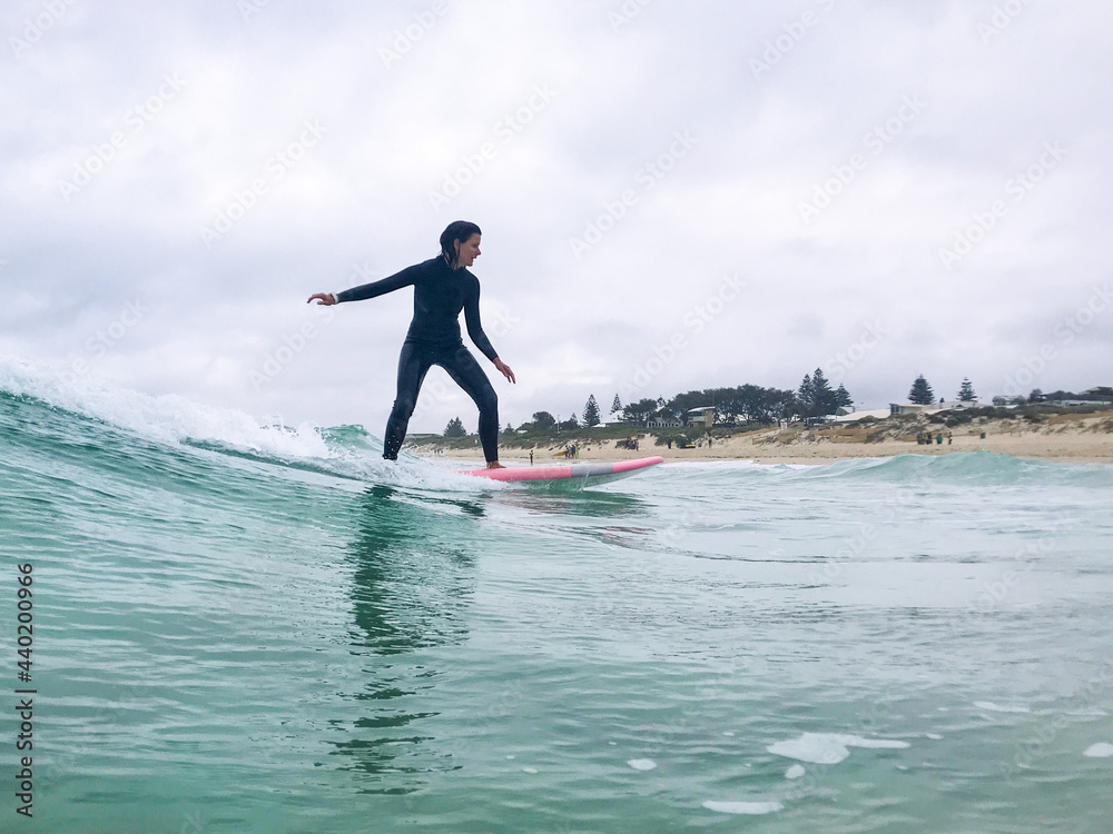 Woman surfing wave on soft board on overcast day Woman surfing wave on soft board on overcast day