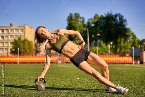 Athletic woman doing strength workout with kettlebell outdoor. High quality photo