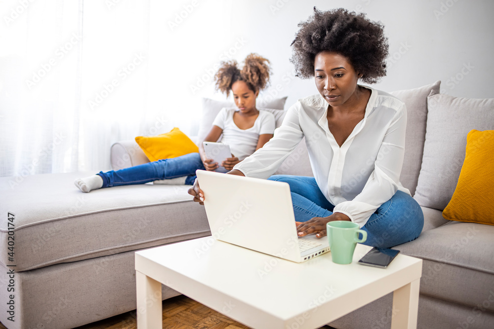 Millennial generation mother working from home with small children while in quarantine isolation during the Covid-19 health crisis. Little girl on tablet computer. Millennial generation mother working from home with small children while in quarantine isolation during the Covid-19 health crisis. Little girl on tablet computer.