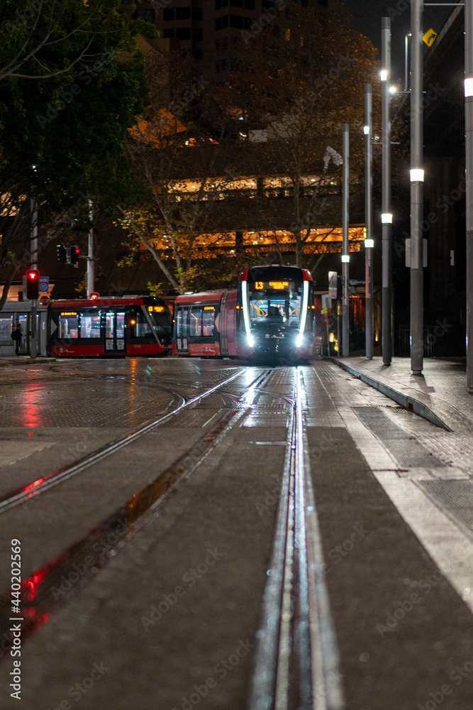Fototapeta premium light rail tram at night pulling into station