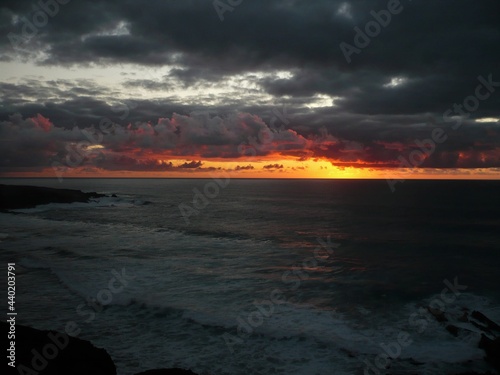 Dramatischer Sonnenuntergang mit dicken dunklen Wolken über dem Meer