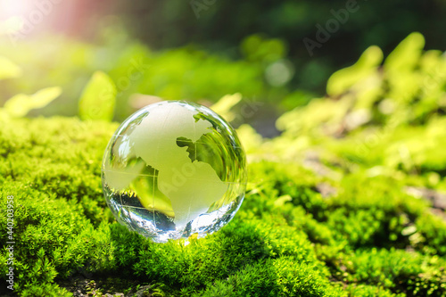 crystal globe glass resting on moss stone with sunshine in nature forset. eco  environment concept © lovelyday12