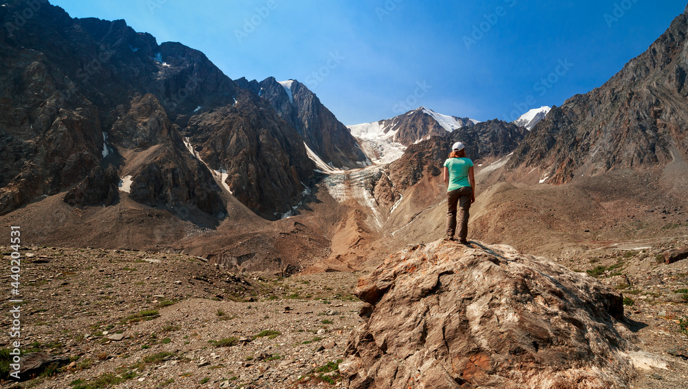 Photo of a tourist girl in the Altai Mountains. In the background is the Bolshoy Aktru Glacier, one of the oldest glaciers in the Altai Mountains. Photo of a tourist girl in the Altai Mountains. In the background is the Bolshoy Aktru Glacier, one of the oldest glaciers in the Altai Mountains.