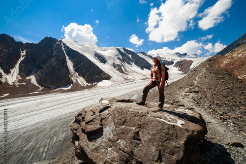 Photo of a tourist girl in the Altai Mountains. In the background is the Bolshoy Aktru Glacier, one of the oldest glaciers in the Altai Mountains.