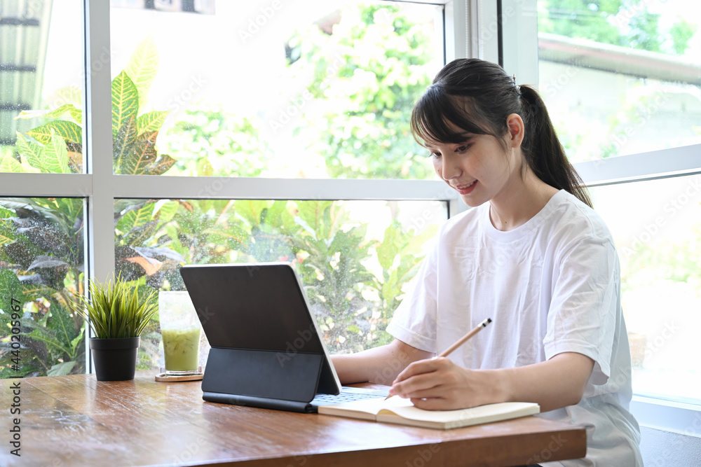 Happy woman studying online with computer tablet at home.