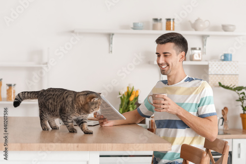 Young man with cute cat rea...