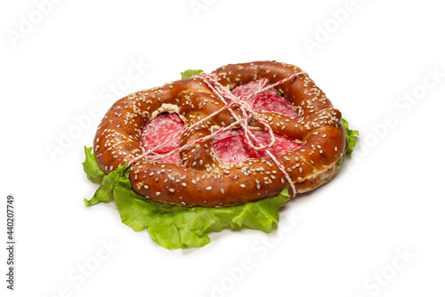 Pretzel with salami and lettuce isolated on a white background.