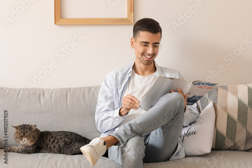 Young man with cute cat rea...