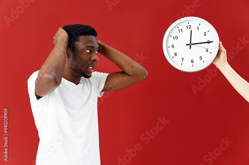 man in surprise looks at his watch in a white t-shirt