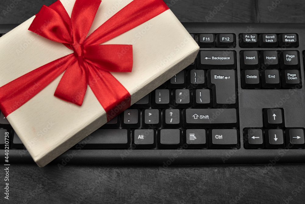 Gift box with red bow on computer keyboard. Ordering the present. Buying gifts online. Gift box with red bow on computer keyboard. Ordering the present. Buying gifts online.