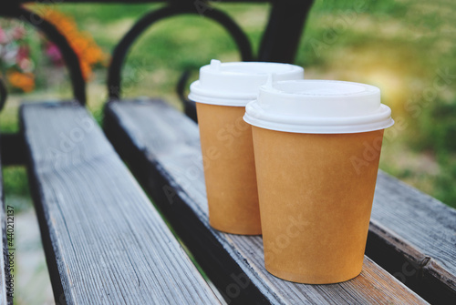 Two cups coffee to take away in park on wooden bench
