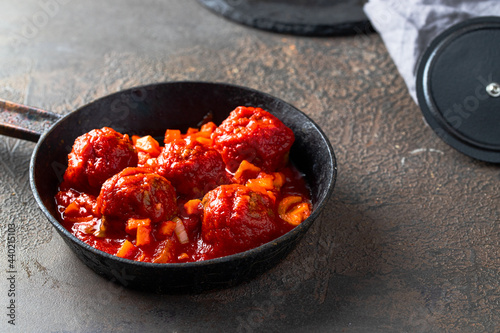 Popular Spanish dish Albondigas or Meatballs with tomato sauce in frying pan on dark background.