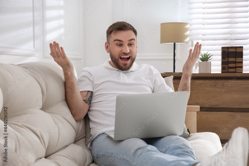 Emotional man participating in online auction using laptop at home Emotional man participating in online auction using laptop at home