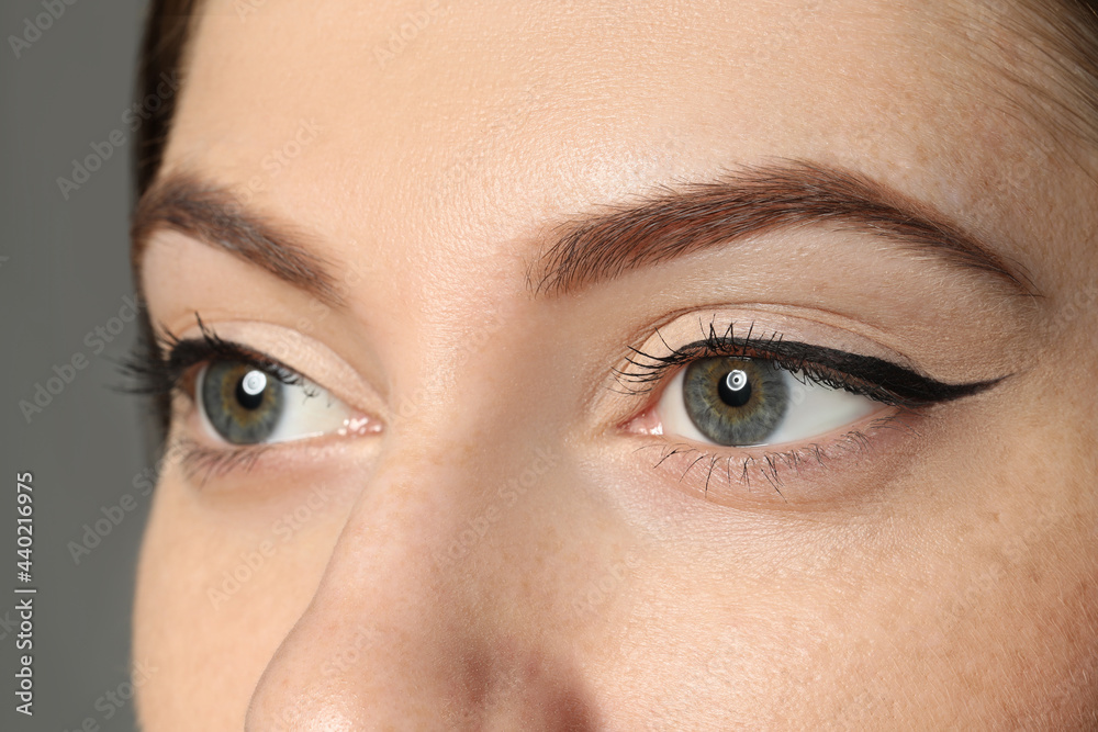 Fototapeta premium Young woman with beautiful eyebrows on grey background, closeup