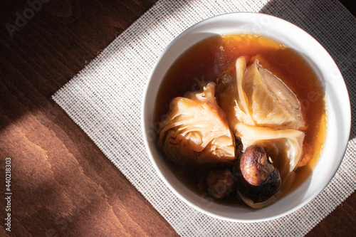 Top view of the traditional food of Asia,Boiled cabbage and shiitake soup with the soy sauce in the white bowl with dried shiitake and all place on the wooden table